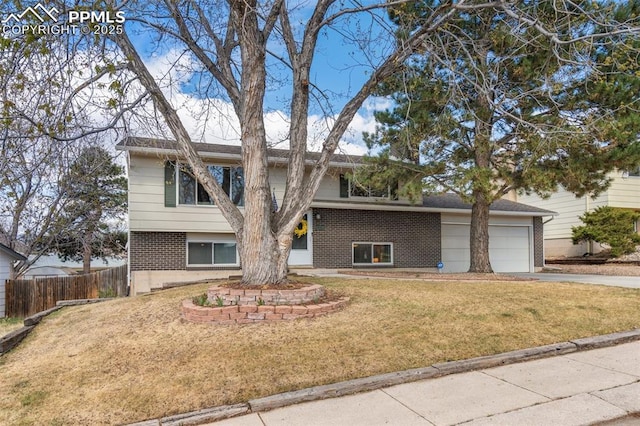 bi-level home with a front lawn, brick siding, concrete driveway, an attached garage, and fence