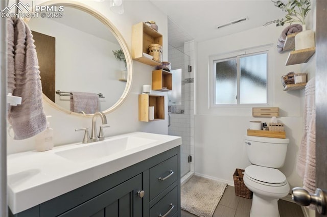 full bath with toilet, vanity, baseboards, visible vents, and a stall shower