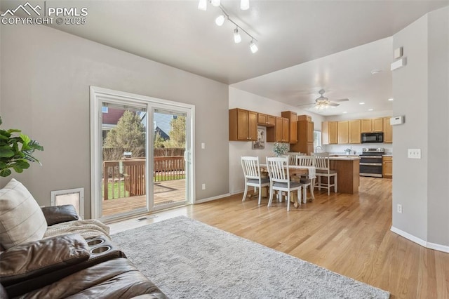 living area with light wood-type flooring, baseboards, and ceiling fan