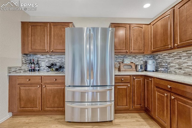 kitchen featuring freestanding refrigerator, brown cabinetry, and light wood-style flooring