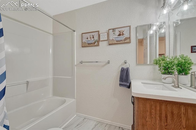 full bathroom featuring shower / tub combo with curtain, vanity, baseboards, a textured wall, and marble look tiles