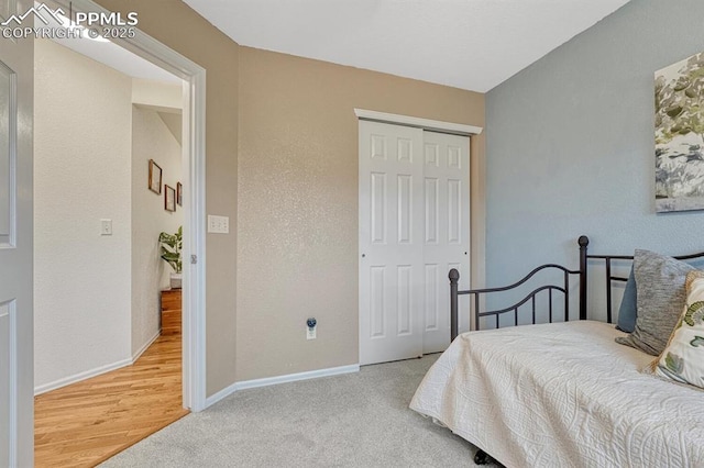 carpeted bedroom with a closet and baseboards
