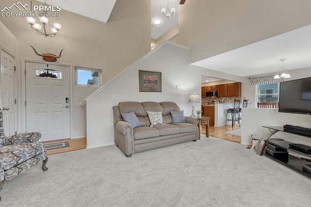 living area featuring a chandelier, light carpet, baseboards, a towering ceiling, and stairway