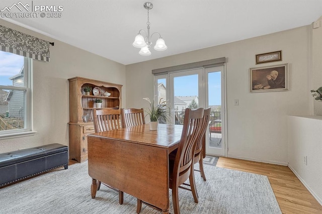 dining room featuring plenty of natural light, a chandelier, light wood finished floors, and baseboards