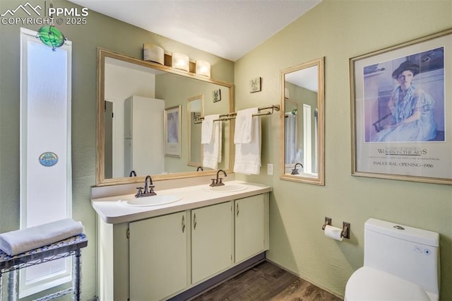 full bath featuring double vanity, wood finished floors, toilet, and a sink