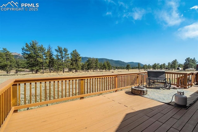 wooden deck featuring a mountain view and an outdoor fire pit