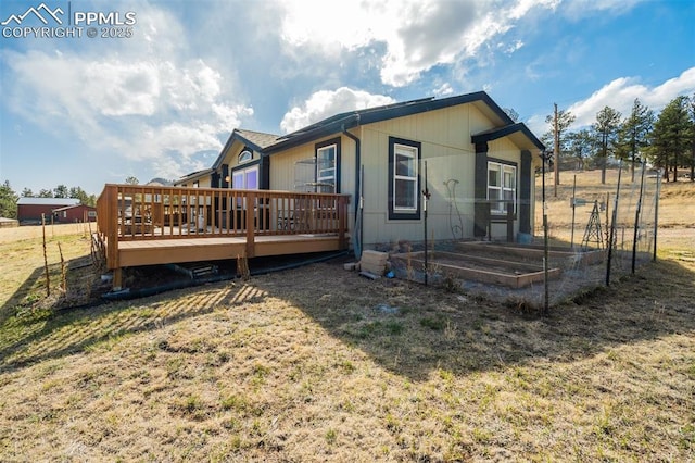 rear view of house with a yard, a vegetable garden, and a wooden deck