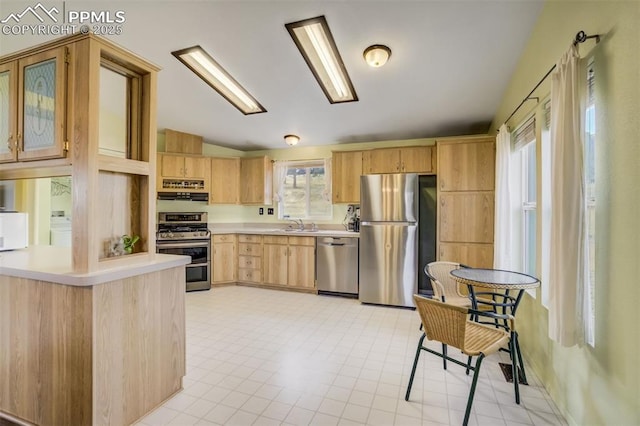 kitchen with light countertops, light brown cabinets, appliances with stainless steel finishes, and lofted ceiling