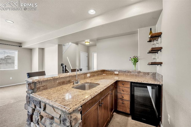 8421 Crooked Branch Ln, Colorado Springs, CO 80927 - kitchen with beverage cooler, baseboards, light colored carpet, light stone counters, and a sink