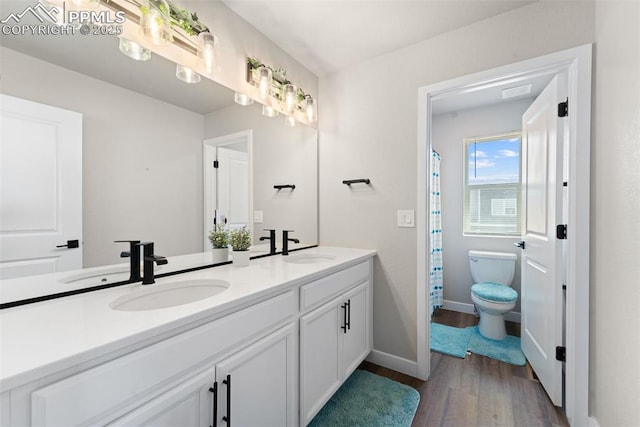 full bath featuring baseboards, wood finished floors, a sink, and toilet