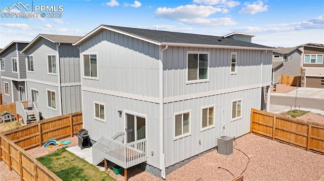 rear view of house featuring a fenced backyard, central air condition unit, board and batten siding, a patio area, and roof with shingles