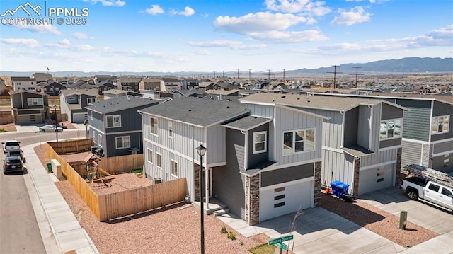 view of front of house featuring fence, a residential view, an attached garage, board and batten siding, and a mountain view