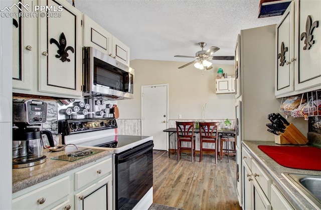 kitchen featuring stainless steel microwave, range with electric cooktop, light countertops, ceiling fan, and light wood-type flooring