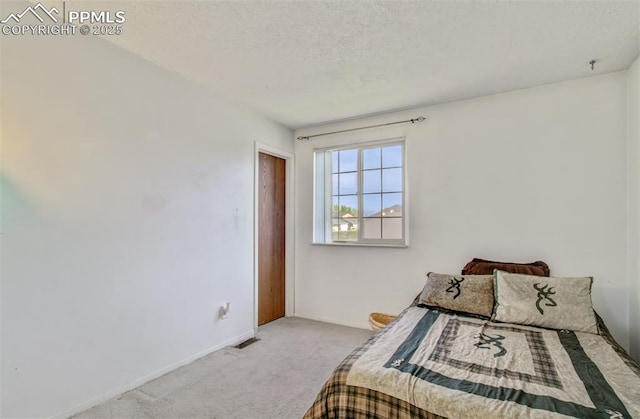carpeted bedroom featuring baseboards, visible vents, and a textured ceiling