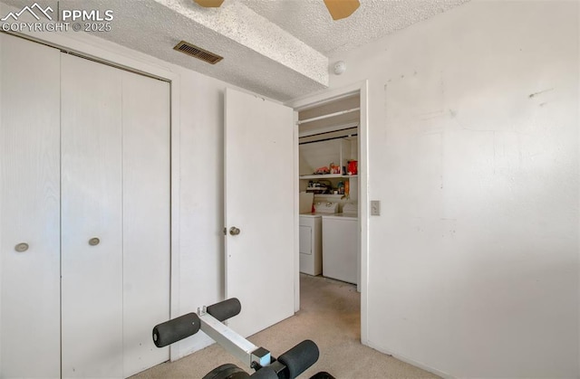 workout room featuring a textured ceiling, independent washer and dryer, visible vents, ceiling fan, and light carpet