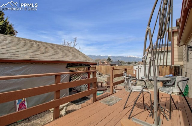 wooden deck with a mountain view and a fenced backyard