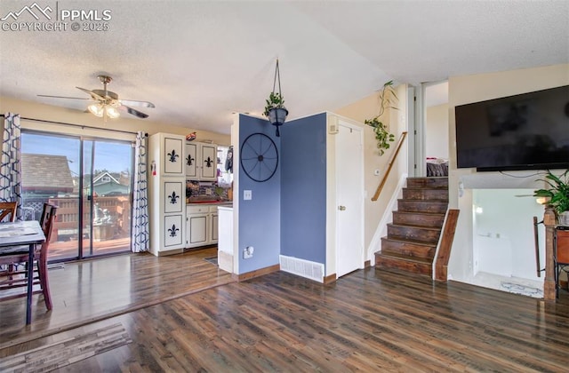 living area featuring ceiling fan, stairs, baseboards, a textured ceiling, and wood finished floors