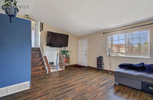 living area with lofted ceiling, visible vents, baseboards, wood finished floors, and stairs