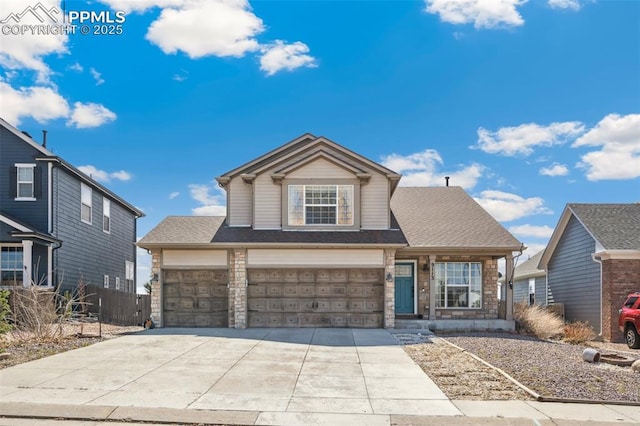 traditional-style home featuring an attached garage, stone siding, concrete driveway, and fence