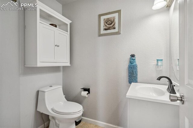 bathroom featuring toilet, vanity, and baseboards
