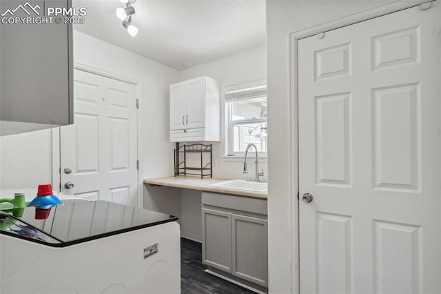 laundry area featuring a sink, cabinet space, and dark wood-style flooring
