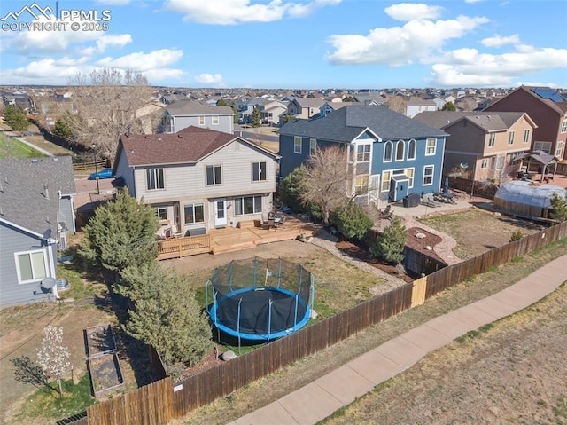 rear view of house featuring a fenced backyard, a residential view, a patio, and a trampoline