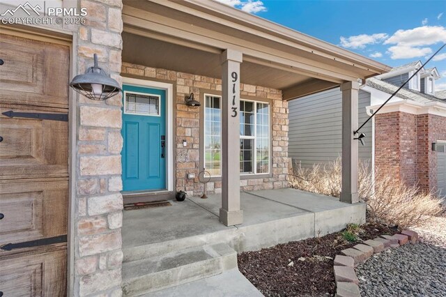 view of exterior entry with a porch and stone siding