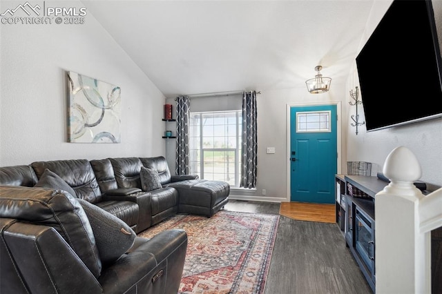 living area featuring dark wood-type flooring, a chandelier, lofted ceiling, and baseboards