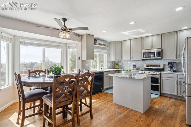 kitchen featuring decorative backsplash, stainless steel appliances, gray cabinetry, and a sink