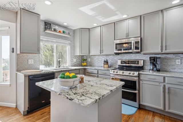 kitchen featuring stainless steel appliances, gray cabinetry, a sink, and light wood-style floors
