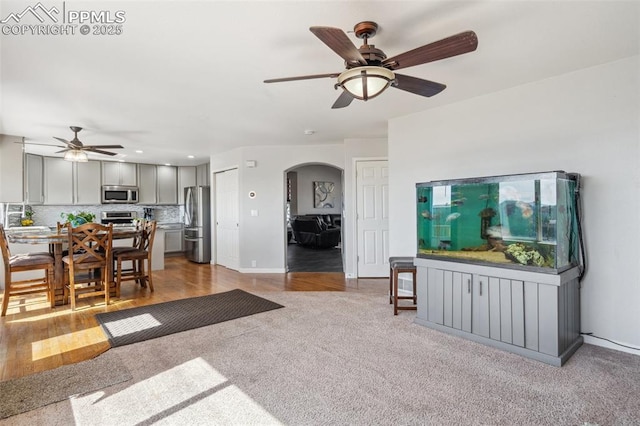 carpeted living room with baseboards, arched walkways, recessed lighting, and ceiling fan