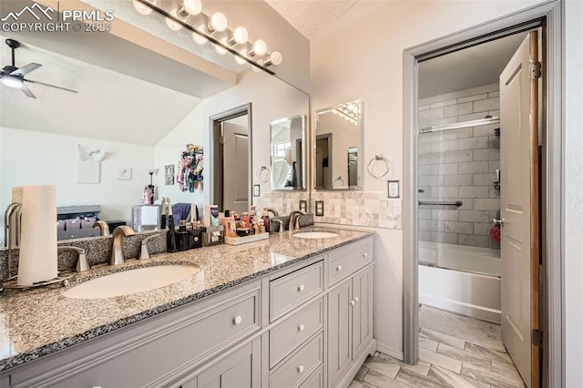 full bath featuring double vanity, a ceiling fan, vaulted ceiling, a sink, and bath / shower combo with glass door