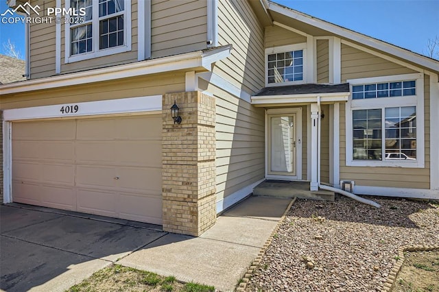 entrance to property with brick siding and a garage