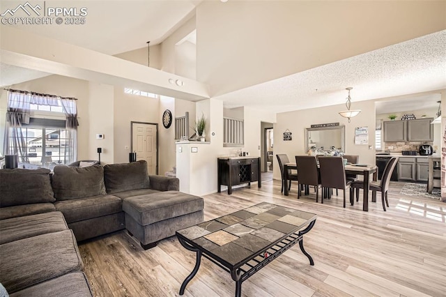 living room featuring light wood-style floors, high vaulted ceiling, and beamed ceiling