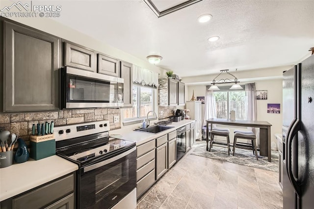 kitchen featuring plenty of natural light, a sink, appliances with stainless steel finishes, and tasteful backsplash