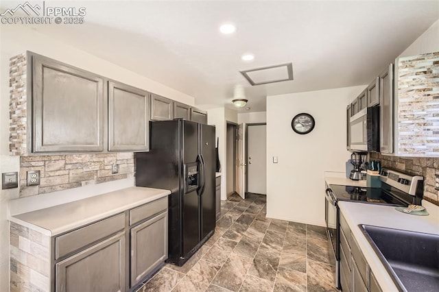 kitchen with backsplash, stone finish flooring, a sink, light countertops, and stainless steel appliances