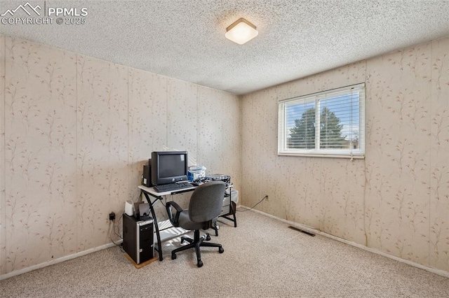 home office with carpet flooring, a textured ceiling, and visible vents