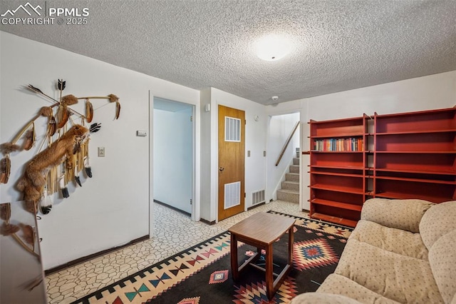 living room with baseboards, visible vents, a textured ceiling, and stairs