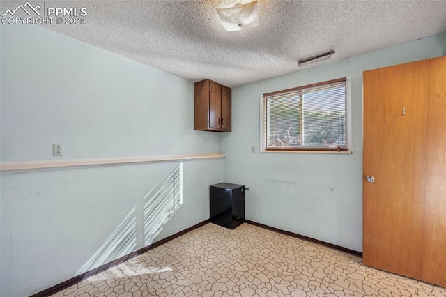 unfurnished room featuring a textured ceiling, visible vents, and baseboards