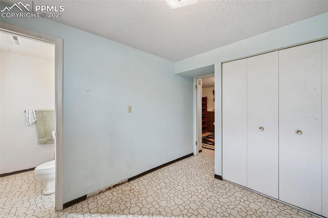 unfurnished bedroom with a textured ceiling, a closet, baseboards, and connected bathroom