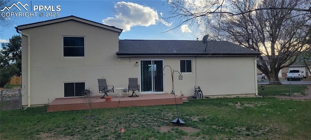 rear view of property featuring roof with shingles, fence, a deck, a yard, and stucco siding