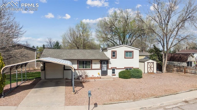 tri-level home with a storage unit, concrete driveway, fence, an outdoor structure, and stucco siding