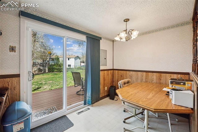 dining space with wainscoting, tile patterned floors, wood walls, and a notable chandelier