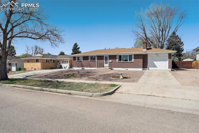 single story home with a chimney, concrete driveway, fence, a garage, and brick siding
