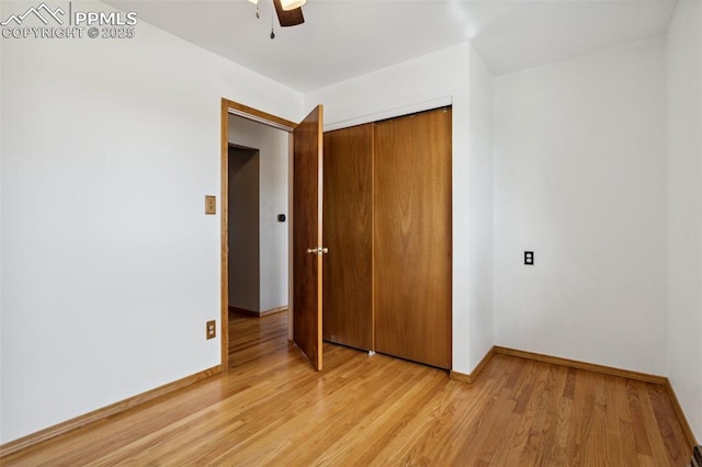 unfurnished bedroom featuring a ceiling fan, baseboards, a closet, and light wood-type flooring