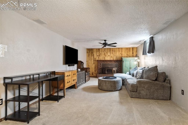 carpeted living room with wood walls, a ceiling fan, a textured ceiling, and visible vents