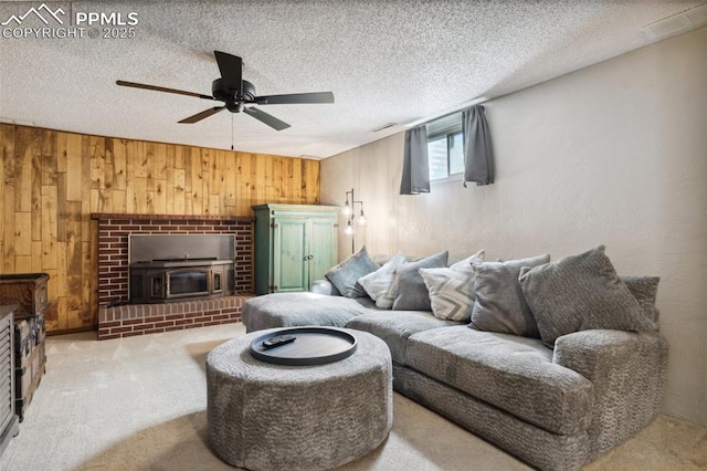 living area featuring wooden walls, visible vents, a ceiling fan, a textured ceiling, and carpet flooring