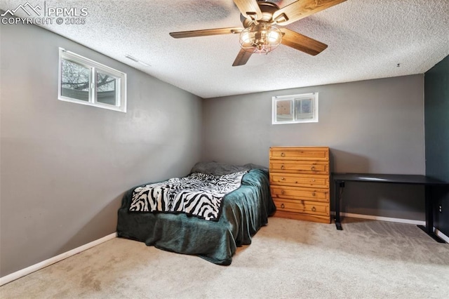 carpeted bedroom featuring a textured ceiling, a ceiling fan, baseboards, and multiple windows