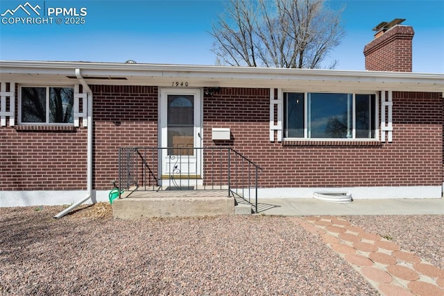 view of front of house featuring a chimney and brick siding