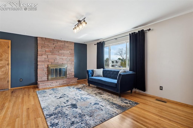 living area with baseboards, wood finished floors, visible vents, and a fireplace